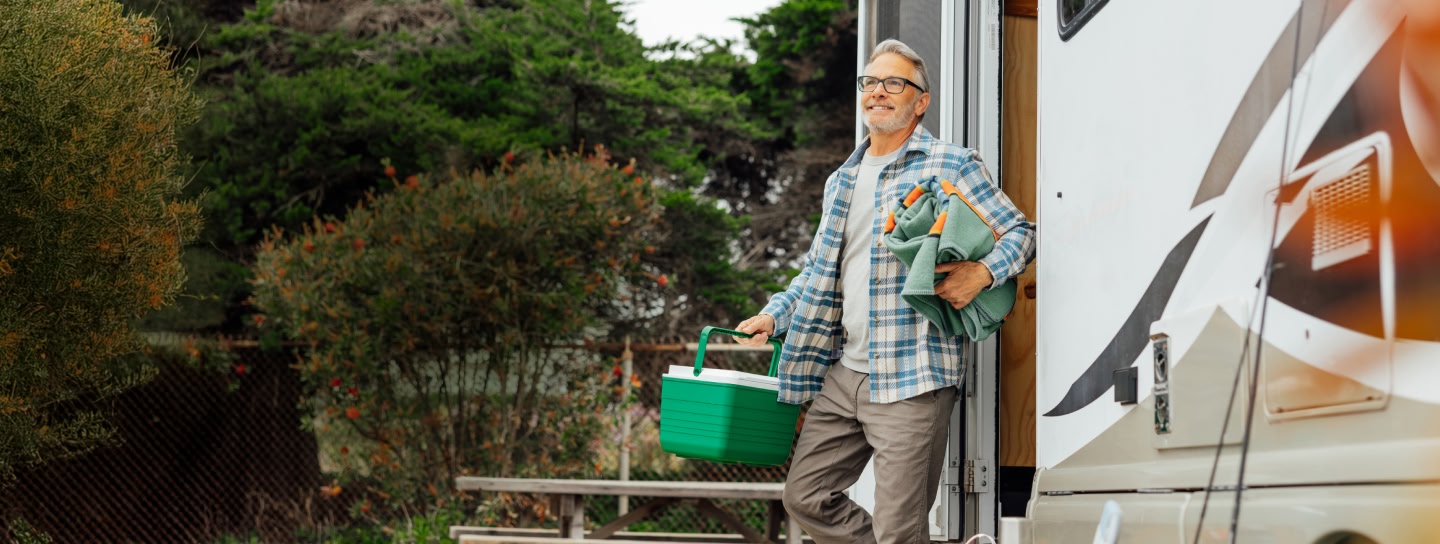 man walking out of camper with cooler and blanket